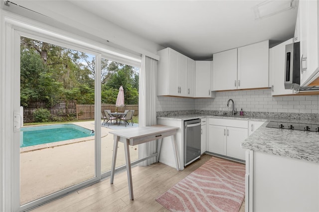 kitchen with a wealth of natural light, light hardwood / wood-style flooring, white cabinets, and stainless steel appliances