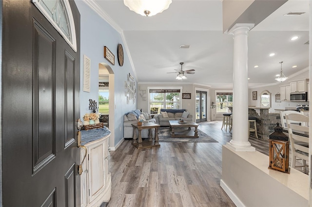 entrance foyer with ornamental molding, ornate columns, lofted ceiling, and wood-type flooring