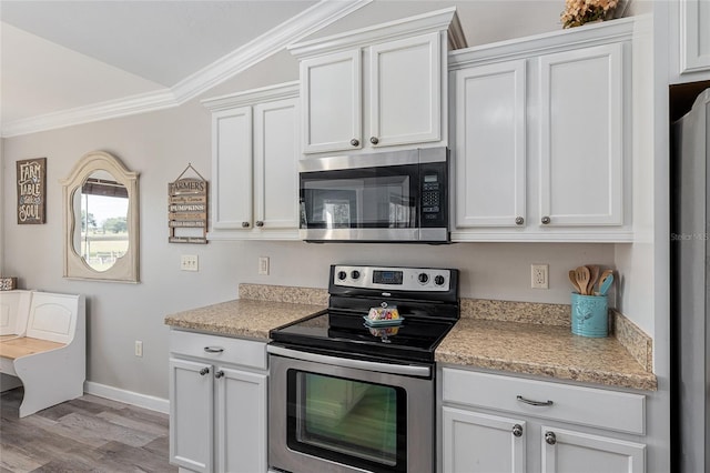 kitchen with crown molding, light hardwood / wood-style flooring, vaulted ceiling, white cabinetry, and stainless steel appliances