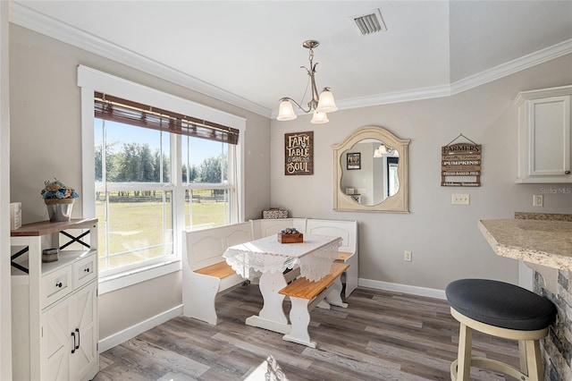 dining room with hardwood / wood-style flooring, a wealth of natural light, an inviting chandelier, and crown molding