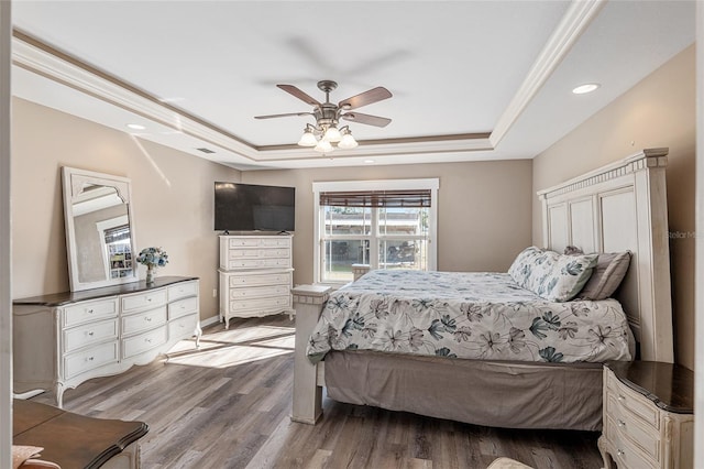 bedroom featuring light wood-type flooring, ceiling fan, a raised ceiling, and ornamental molding