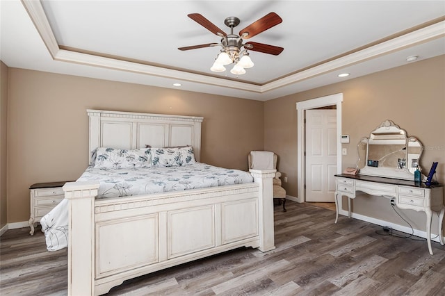 bedroom featuring ceiling fan, a tray ceiling, dark hardwood / wood-style floors, and crown molding