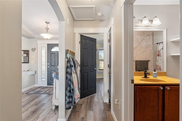 foyer entrance with sink, ornamental molding, and light hardwood / wood-style floors