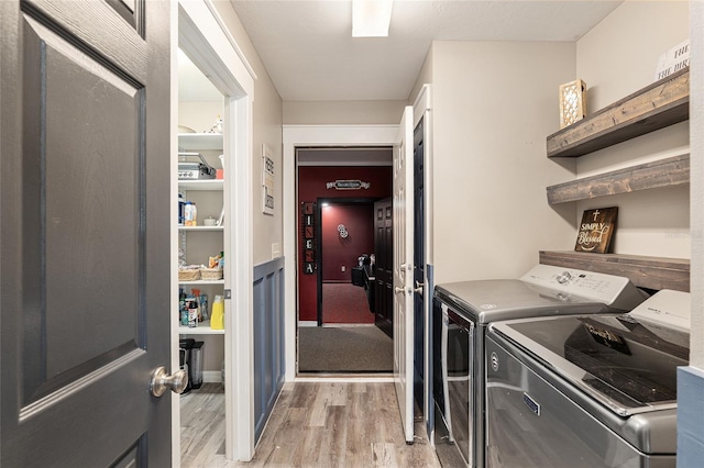 clothes washing area featuring washer and clothes dryer and light hardwood / wood-style flooring