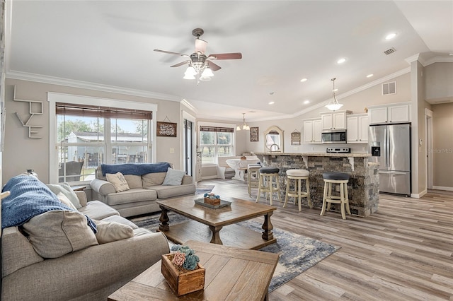 living room with light hardwood / wood-style floors, crown molding, and lofted ceiling