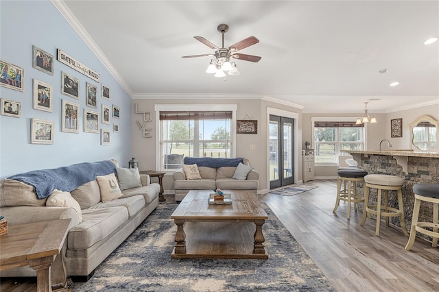 living room with hardwood / wood-style flooring, a wealth of natural light, ornamental molding, and vaulted ceiling