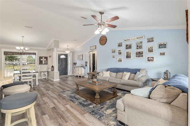 living room with ceiling fan with notable chandelier, hardwood / wood-style floors, ornamental molding, vaulted ceiling, and decorative columns