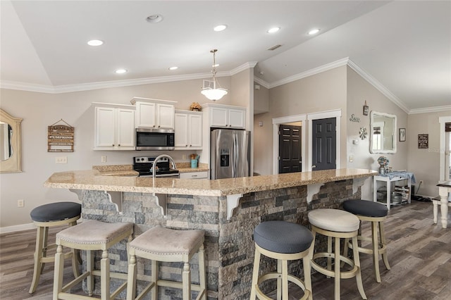 kitchen with a kitchen bar, white cabinetry, vaulted ceiling, and stainless steel appliances