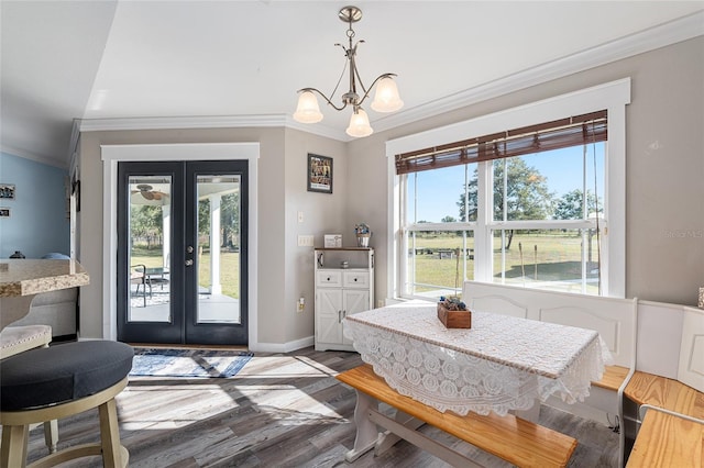 dining area with crown molding, hardwood / wood-style flooring, a notable chandelier, and french doors