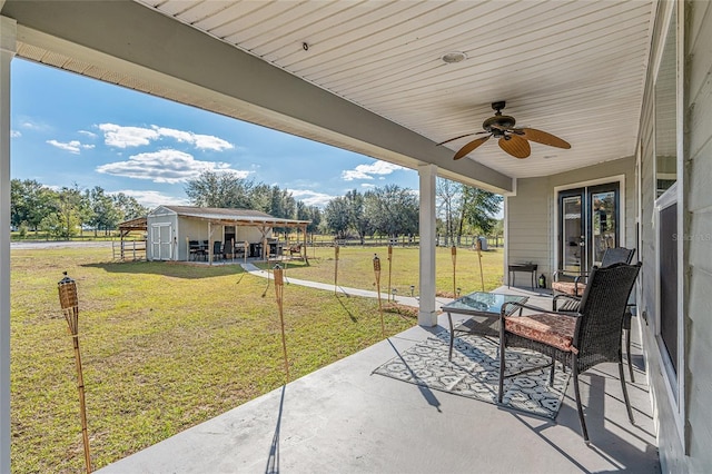 view of patio with ceiling fan and a shed