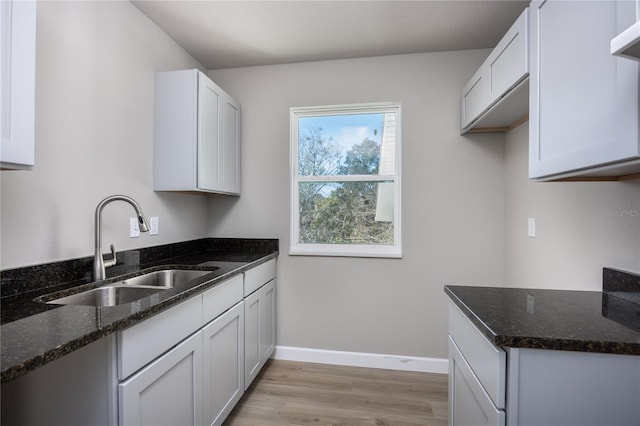 kitchen featuring white cabinets, sink, and dark stone counters