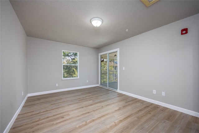 empty room with light hardwood / wood-style floors and a textured ceiling