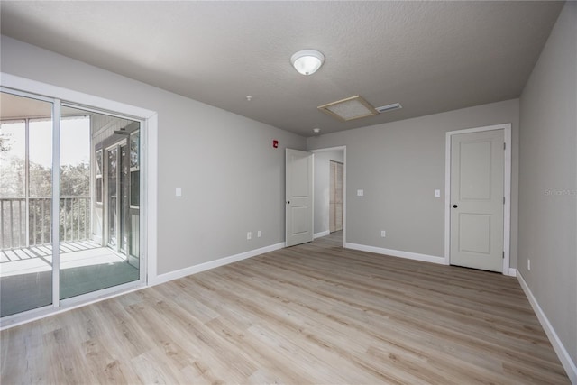 empty room featuring a textured ceiling and light hardwood / wood-style floors