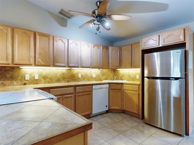 kitchen with ceiling fan, dishwasher, sink, stainless steel fridge, and vaulted ceiling