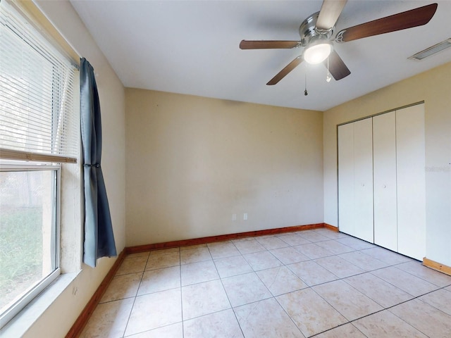 unfurnished bedroom with light tile patterned floors, a closet, and ceiling fan