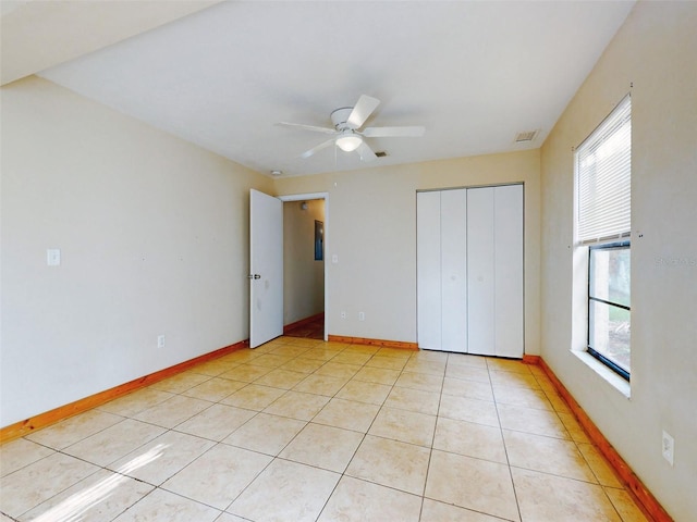 unfurnished bedroom with ceiling fan, light tile patterned flooring, a closet, and multiple windows