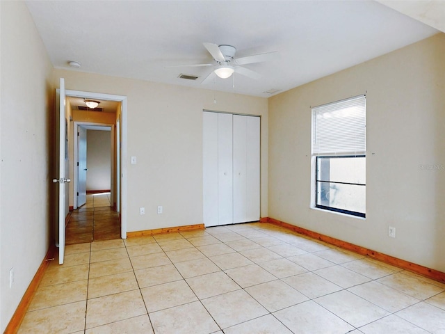 unfurnished bedroom featuring ceiling fan, a closet, and light tile patterned flooring