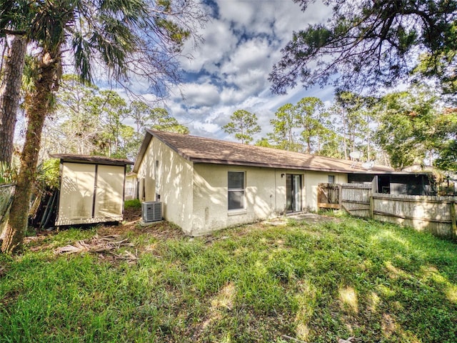 rear view of property with central AC unit and a storage unit