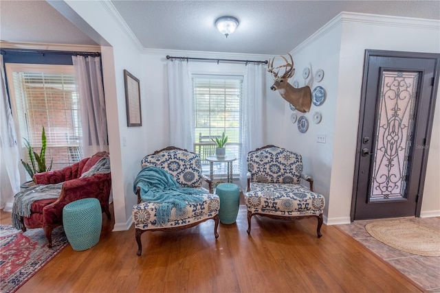 sitting room with hardwood / wood-style floors, ornamental molding, and a textured ceiling