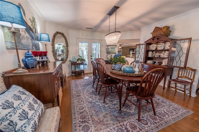 dining area featuring crown molding, hardwood / wood-style floors, french doors, and a notable chandelier