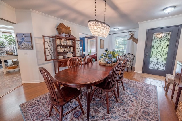 dining room with light wood-type flooring, crown molding, and an inviting chandelier