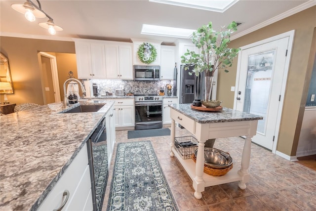 kitchen featuring appliances with stainless steel finishes, a skylight, light stone counters, sink, and white cabinetry