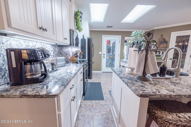 kitchen featuring white cabinets, ornamental molding, appliances with stainless steel finishes, and a skylight