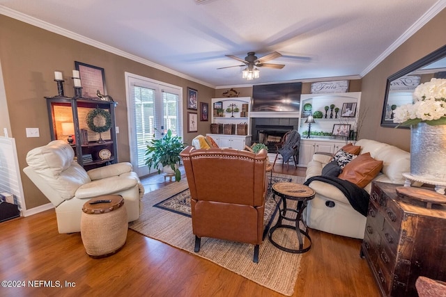 living room with hardwood / wood-style floors, ceiling fan, a fireplace, and crown molding