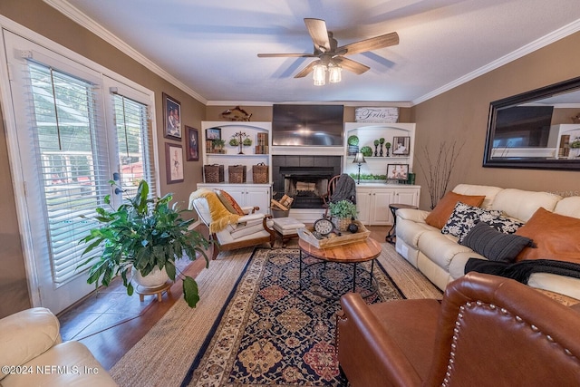 living room with a tile fireplace, light wood-type flooring, ceiling fan, and ornamental molding