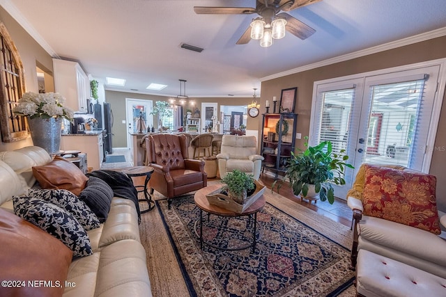 living room featuring french doors, tile patterned flooring, ceiling fan with notable chandelier, and ornamental molding