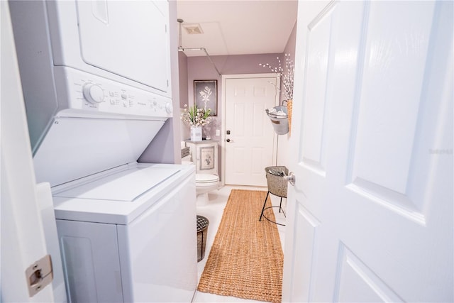 laundry area with light tile patterned floors and stacked washing maching and dryer