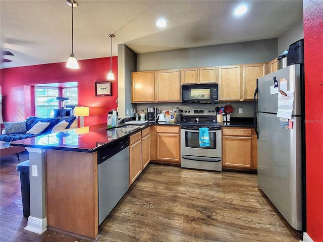 kitchen featuring dark wood-type flooring, sink, hanging light fixtures, kitchen peninsula, and stainless steel appliances