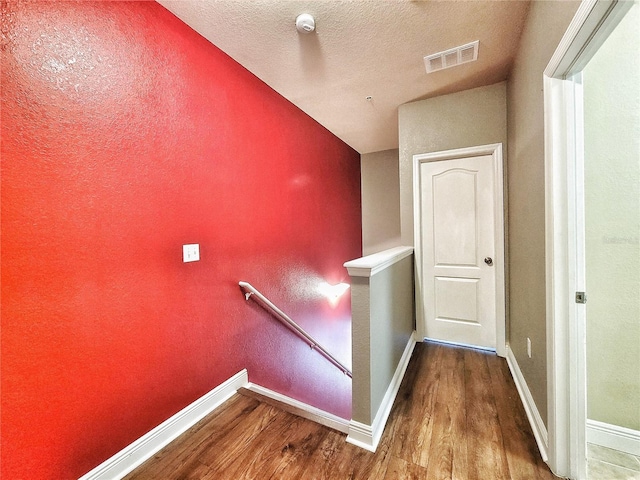 staircase with hardwood / wood-style floors and a textured ceiling