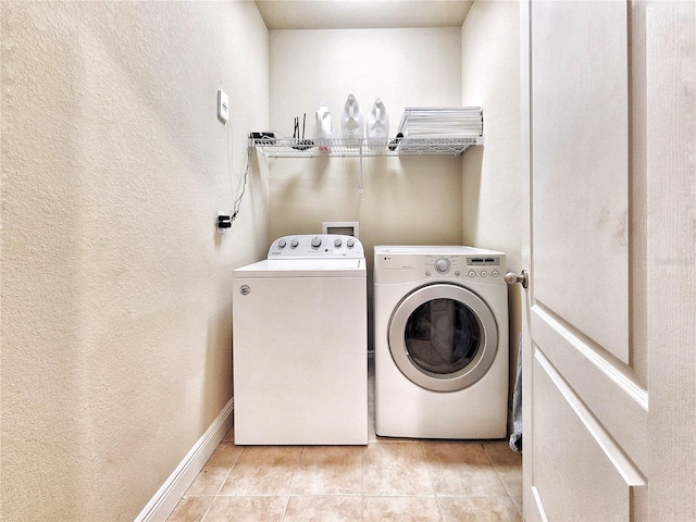 clothes washing area featuring light tile patterned floors and washing machine and clothes dryer