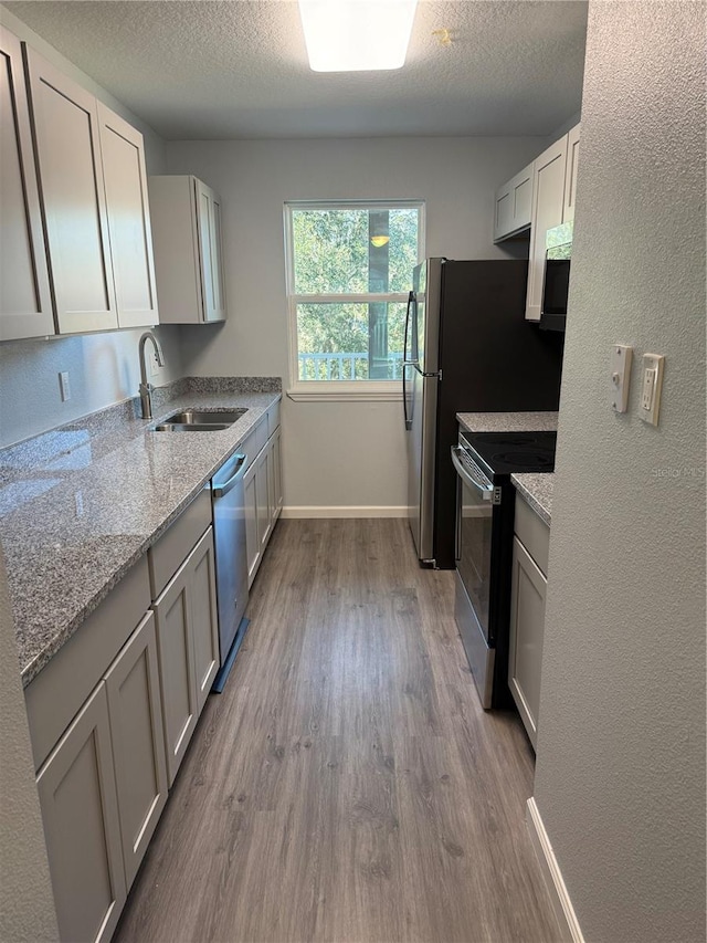 kitchen with white cabinets, sink, a textured ceiling, appliances with stainless steel finishes, and light hardwood / wood-style floors