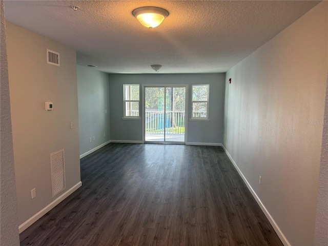 spare room with dark hardwood / wood-style floors and a textured ceiling