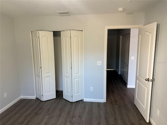 unfurnished bedroom with a closet, dark hardwood / wood-style flooring, and a textured ceiling