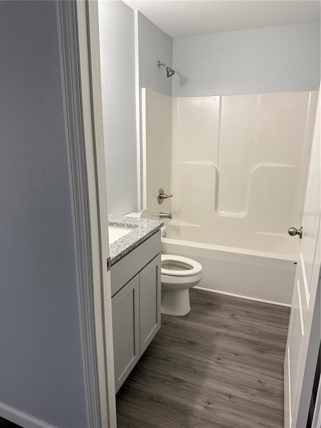 full bathroom featuring vanity, a textured ceiling, toilet, shower / bathing tub combination, and hardwood / wood-style flooring