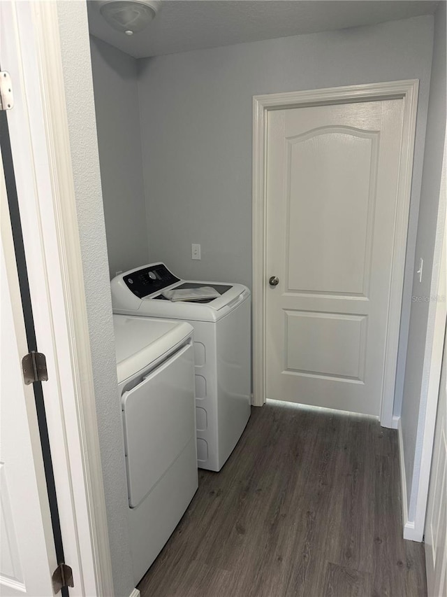 clothes washing area with dark hardwood / wood-style floors and washing machine and clothes dryer