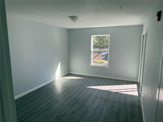 empty room featuring a textured ceiling and dark hardwood / wood-style flooring