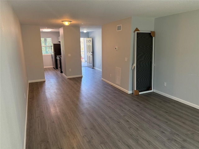 empty room with a textured ceiling and dark hardwood / wood-style floors