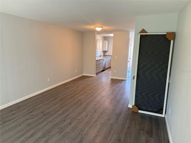 unfurnished living room featuring a textured ceiling, sink, and dark hardwood / wood-style floors