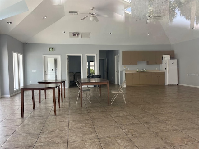 dining space featuring a wood stove, ceiling fan, high vaulted ceiling, and light tile patterned floors