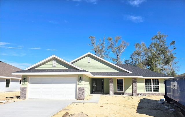 ranch-style house with concrete driveway, an attached garage, stone siding, and roof with shingles