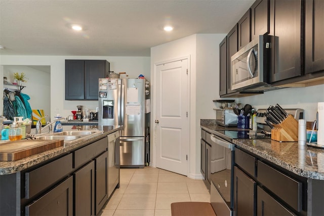 kitchen featuring a center island, sink, dark stone countertops, appliances with stainless steel finishes, and light tile patterned flooring