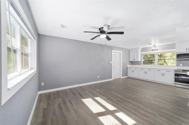 unfurnished living room featuring ceiling fan, dark wood-type flooring, and a textured ceiling