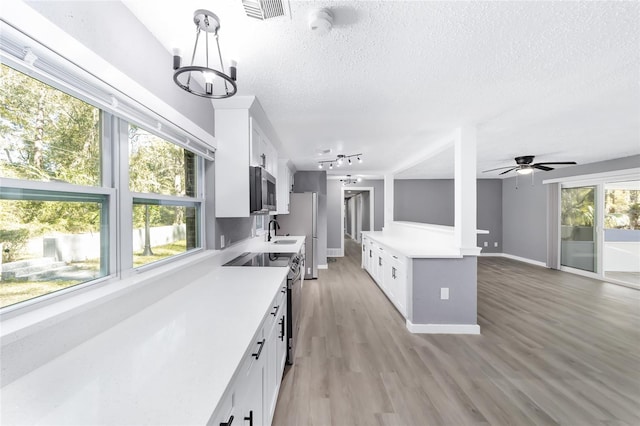 kitchen featuring light hardwood / wood-style floors, white cabinetry, stainless steel appliances, and a healthy amount of sunlight