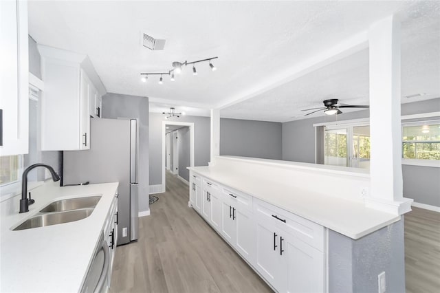 kitchen featuring white cabinetry, sink, ceiling fan, light hardwood / wood-style floors, and a textured ceiling