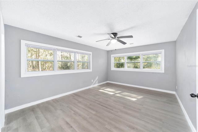 unfurnished room with ceiling fan, light wood-type flooring, and a textured ceiling