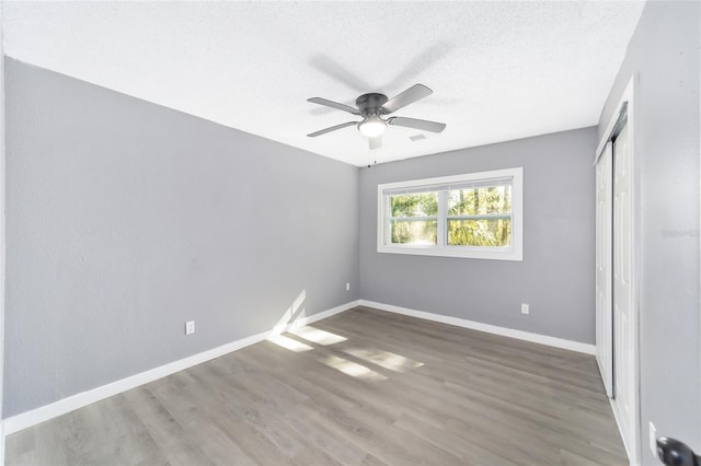 unfurnished bedroom featuring a textured ceiling, a closet, dark hardwood / wood-style floors, and ceiling fan